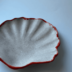 Ręcznie wykonana ceramiczna miseczka w kształcie muszelki, w kolorze szarym z czerwonym obramowaniem, idealna na biżuterie